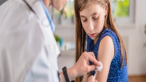 Doctor giving a young girl a vaccine shot